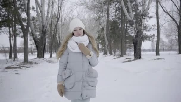 降雪時に冬の森の中で自然を楽しむ4K深刻なかわいい女の子が歩く — ストック動画