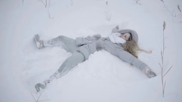 快乐美丽的女人躺在地上 使雪天使在温特 — 图库视频影像