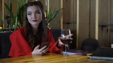 Genç kadın akıllı telefon ve Içme kırmızı şarap manifatura