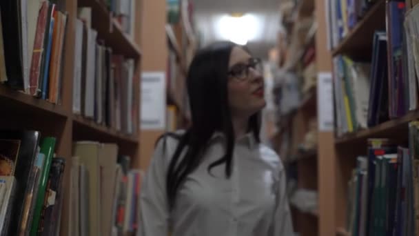 Beautiful Girl Closes Book Walks Bookshelves Smile — стоковое видео
