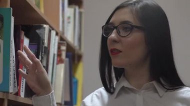 güzel kız kütüphanede kitap seçimi