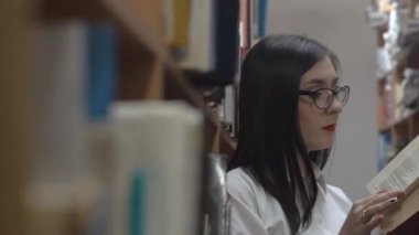 Kütüphanede kitap okuyan genç bir kadın.