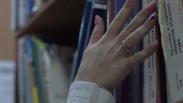 図書館の本棚に本を保管する女性の手のスローモーション — ストック動画