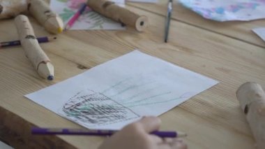 Küçük kız yeşil kalem kağıt üzerinde çizer.