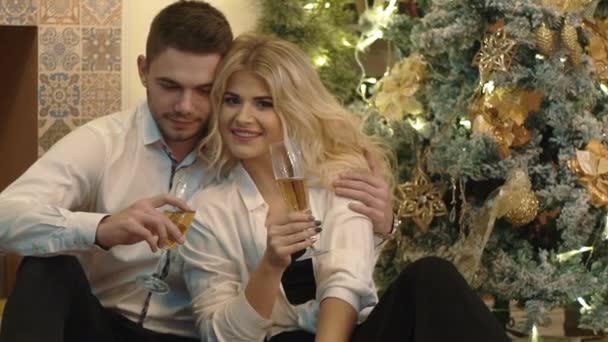 慢动作夫妇坐在圣诞树附近 喝香槟 — 图库视频影像