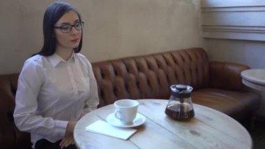 4k bir güzel kız bir kafe ve bir fincan Içine çay pours oturur.