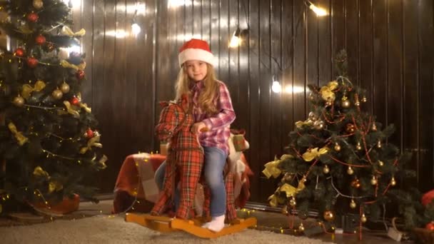 Kleines Kind Mit Weihnachtsmütze Sitzt Auf Schaukelpferd — Stockvideo