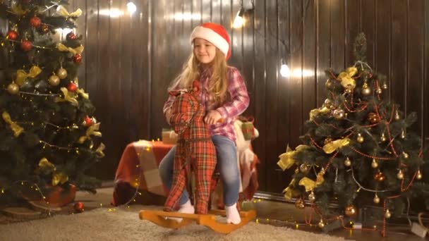 Klein Schattig Meisje Zit Rocking Horse Kamer Buurt Van Kerstboom — Stockvideo