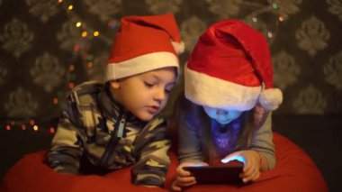 Abim ve kız kardeşim Noel ağacının önünde telefondalar..
