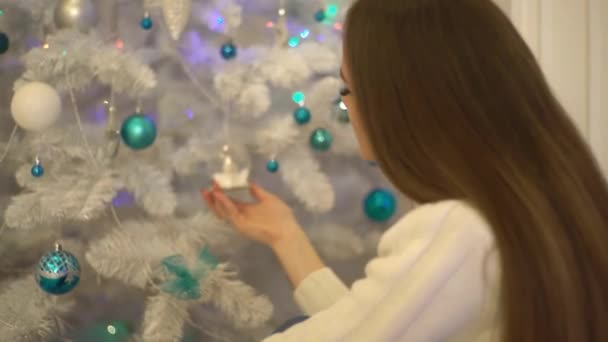 デコで白と白のクリスマスボールに触れる幸せな魅力的な若い女性 — ストック動画