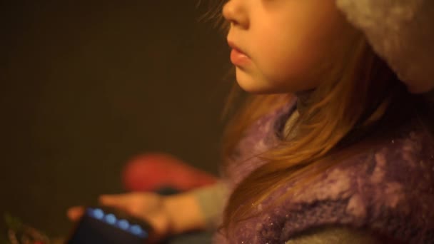 可爱的小女孩使用智能手机 在圣诞树前 特写镜头 — 图库视频影像