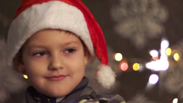 Enfant dans un chapeau de Noël près d'un arbre de Noël avec un feu du Bengale .