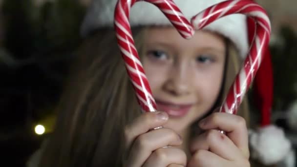 小さな女の子はキャンディケーンズでハート形を作ります 彼女は休日喜びと笑顔 — ストック動画
