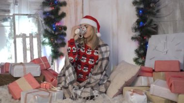 Noel dekore edilmiş oda katta oturan sıcak içecek bir fincan kadınla.