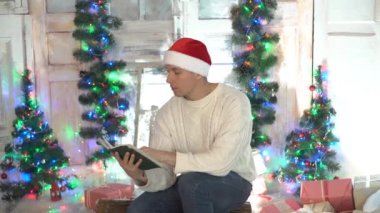 Koltukta kitap okuyan adam, Arka planda Noel ağacı.