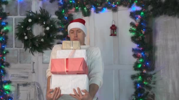 家のクリスマス ツリーの近くに立って 大人の男の笑みを浮かべて 贈り物を保持して — ストック動画