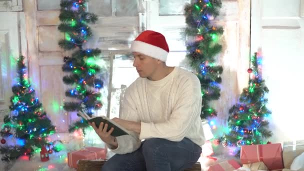Άνθρωπος Ανάγνωση Βιβλίο Στον Καναπέ Χριστουγεννιάτικο Δέντρο Στο Παρασκήνιο — Αρχείο Βίντεο
