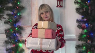 Noel hediyesi tutarak ağacı önünde tanınmayan kadın.