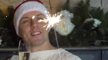 Noel adam topları ağaç arka plan üzerinde bir kadeh köpüklü şarap içer.