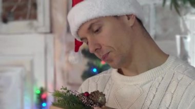 Kutudaki harika hediyeye bakan mutlu adam, arka plandaki Noel ağacı..