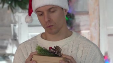 Büyüleyici Adam Kutuda Sihirli Hediyeye Bakıyor, Arka planda Noel Ağacı.