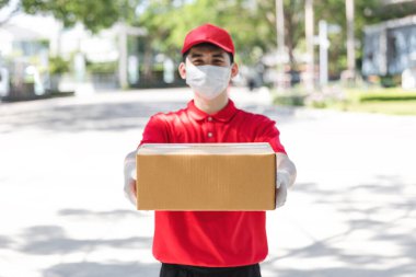 Asyalı kurye elinde plastik eldiven ve maskeyle karton kutular tutuyor, online alışveriş ve ekspres teslimatı, servis karantina salgını Coronavirus virüsü konsepti.