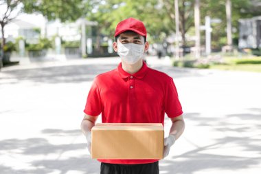 Asyalı kurye elinde plastik eldiven ve maskeyle karton kutular tutuyor, online alışveriş ve ekspres teslimatı, servis karantina salgını Coronavirus virüsü konsepti.