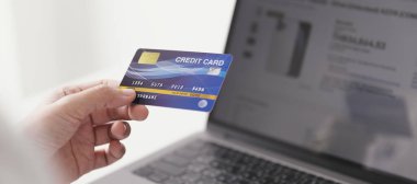 Kredi kartı tutan ve dizüstü bilgisayar kullanan iş kadını, evde çalışan iş kadını, online alışveriş, e-ticaret, harcama parası, internet bankacılığı, ev konseptinden iş.