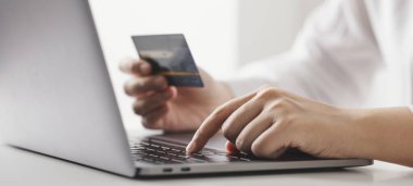 Kredi kartı tutan ve dizüstü bilgisayar kullanan iş kadını, evde çalışan iş kadını, online alışveriş, e-ticaret, harcama parası, internet bankacılığı, ev konseptinden iş.