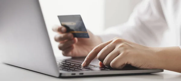 Kredi kartı tutan ve dizüstü bilgisayar kullanan iş kadını, evde çalışan iş kadını, online alışveriş, e-ticaret, harcama parası, internet bankacılığı, ev konseptinden iş.