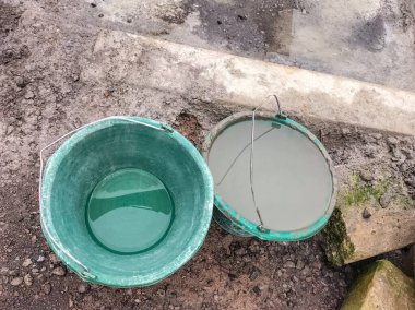 İnşaat alanında içi bulanık su dolu bir kova. Köyde tadilat yapılıyor. Seçici odak.