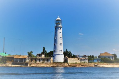 Eski beyaz deniz feneri çevrili plaj evleri