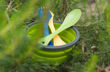Tourist tableware among spruce. Fir branches. Green composition. Front view on a plate. clipart