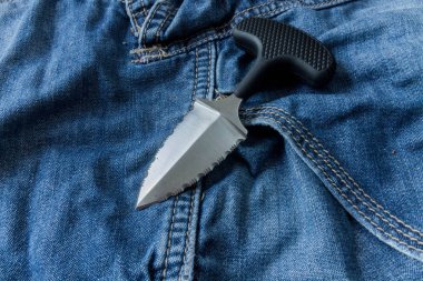 Tırtıklı bıçak jeanse arka plan üzerinde... Yakın çekim. Çakısı.