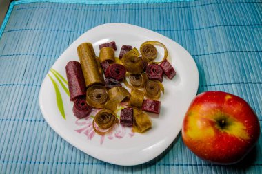 Çeşitli tatlılar plaka üzerinde. Çok renkli tatlılar ve bir elma. Tatlılar meyve ve çilek.