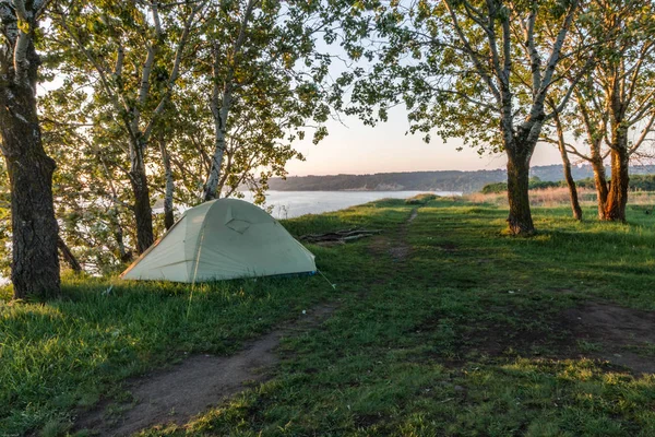 Early morning in a tourist tent. A tourist tent on the river bank between the trees.