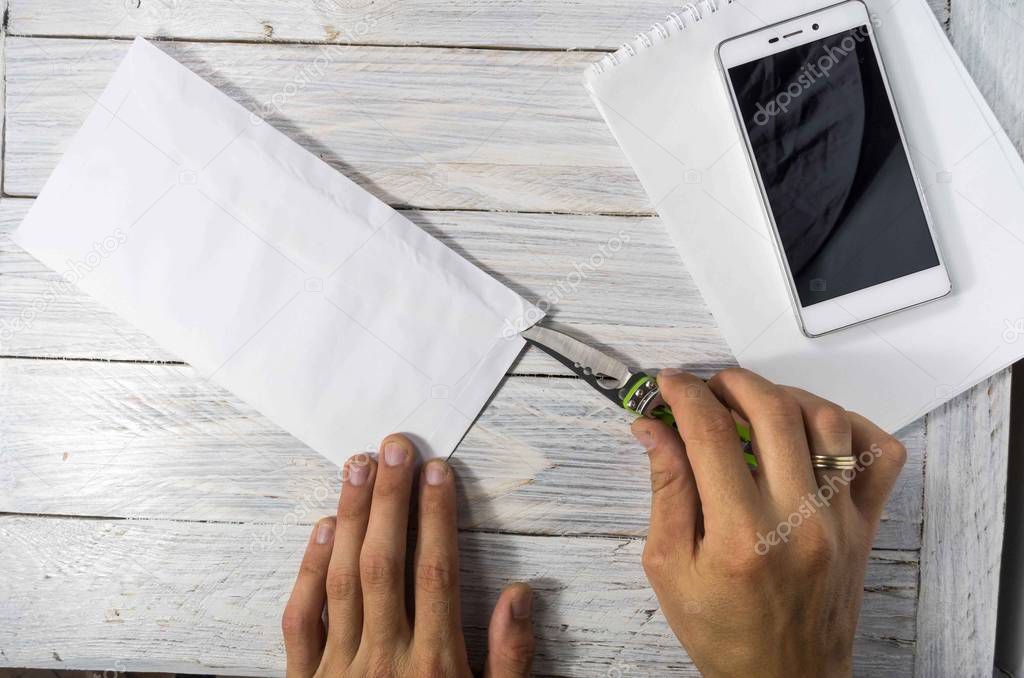 Man opens the envelope with a knife in the workplace. Office place.