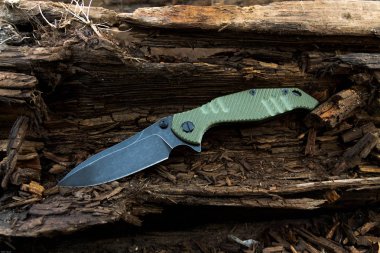 Bıçağın kahverengi ahşap üstüne. Siyah bıçak. Yeşil tutamacın.