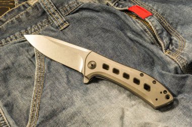 Titanyum saplı bıçak katlanır. Hafif bıçak sapı. Titanyum bıçak sapı. Kot arka plan.