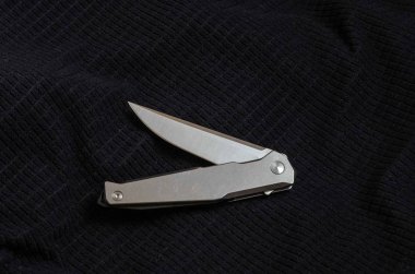 Bir bükülmüş pozisyonda metal saplı bıçak. Siyah tekstil.