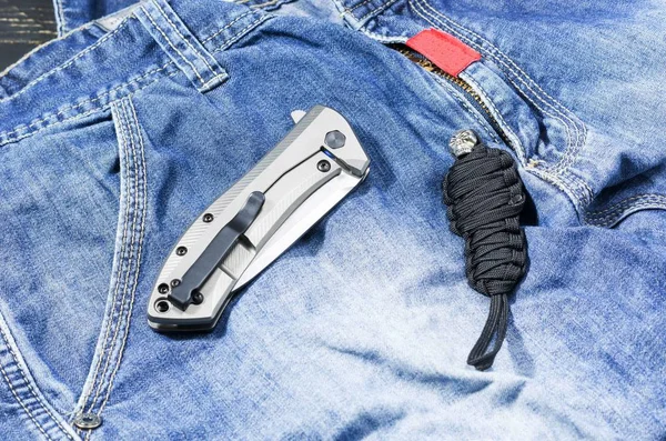 Nóż Metalowym Uchwytem Złożonej Formie Denim Tła Łańcuch Paracordu Dżinsy — Zdjęcie stockowe