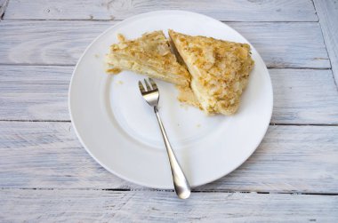 Adet puf pasta tatlı çatal ile beyaz tabakta. Beyaz ahşap zemin.