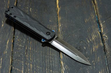 Siyah bıçak siyah arka plan üzerine katlanır. Ahşap arka plan. Köşegen.