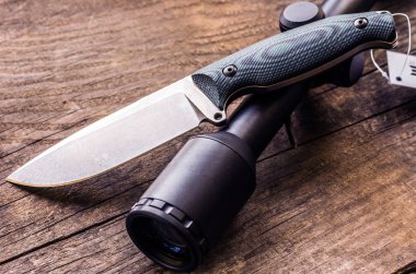 Avcılık kompozisyon. Av bıçağı ve optik görüş. Yaşlı bir ağaç arka plan.