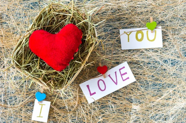 Red heart in a basket with hay. Rural type. I love you.