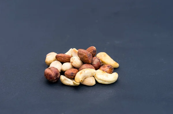 A variety of nuts on a black background. Front view.