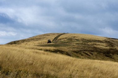 Traktör dağlarda. Dağın zirvesine giden yol. Sarı sonbahar çimleri.