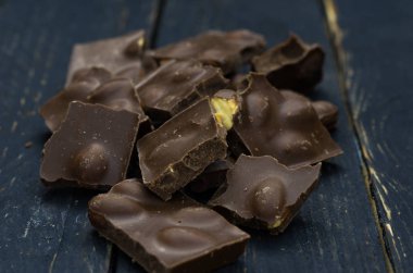 Fındık ile sütlü çikolata. Karanlık fotoğraf. Ahşap arka plan üzerinde çikolata.