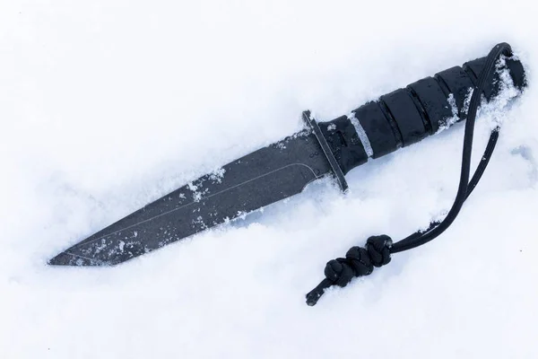 Tactical knife in snow. Military knife with lanyard.