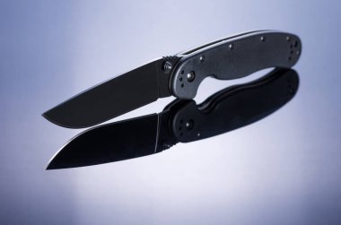 Bıçak ve onun yansıması cam katlanır. Masanın ortasında bıçak. Önden görünüm.